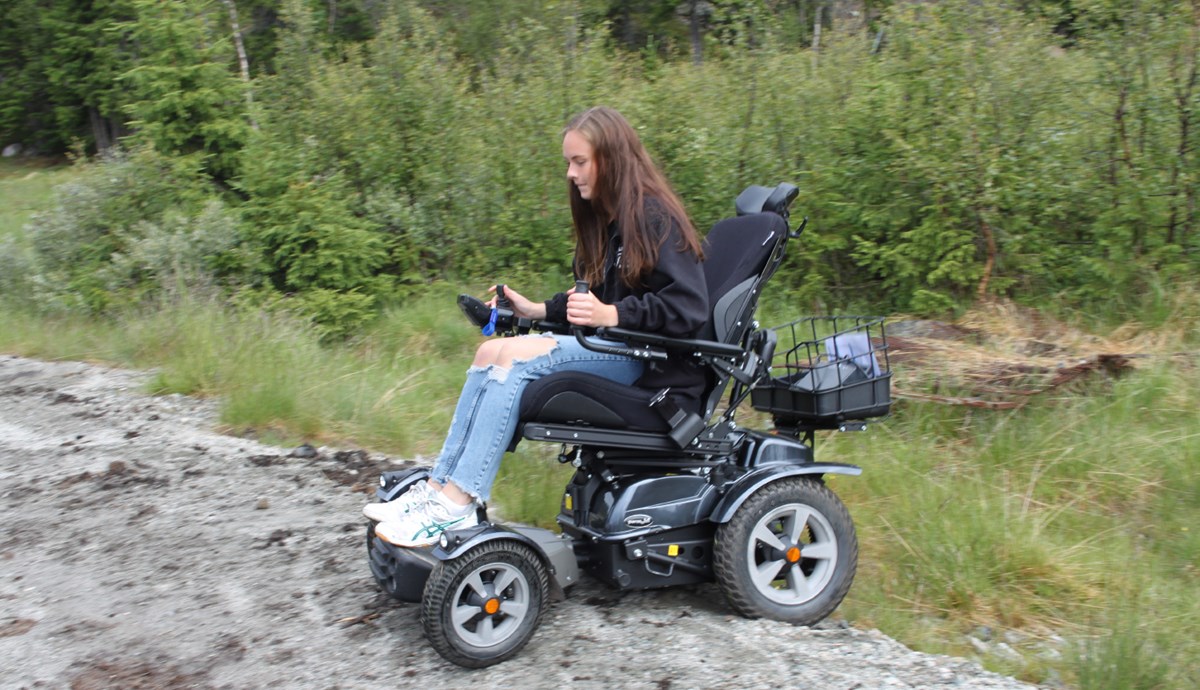 Thea demonstrerer en av de elektriske rullestolene som publikum kan få prøve.